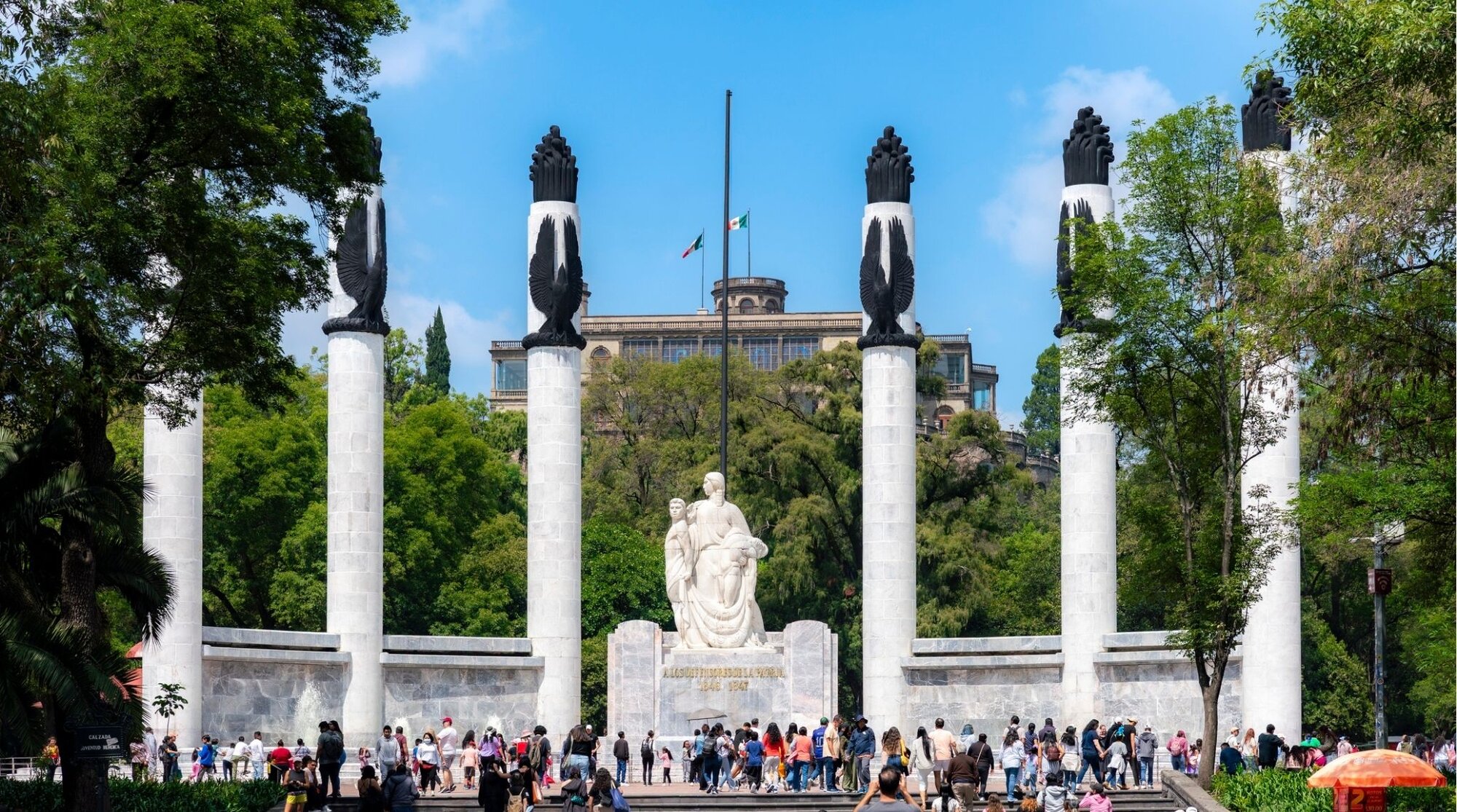  Viajantes explorando o Altar à Pátria, o monumento aos Niños Héroes, situado no Bosque de Chapultepec com a imponente silhueta do Castelo ao fundo.
