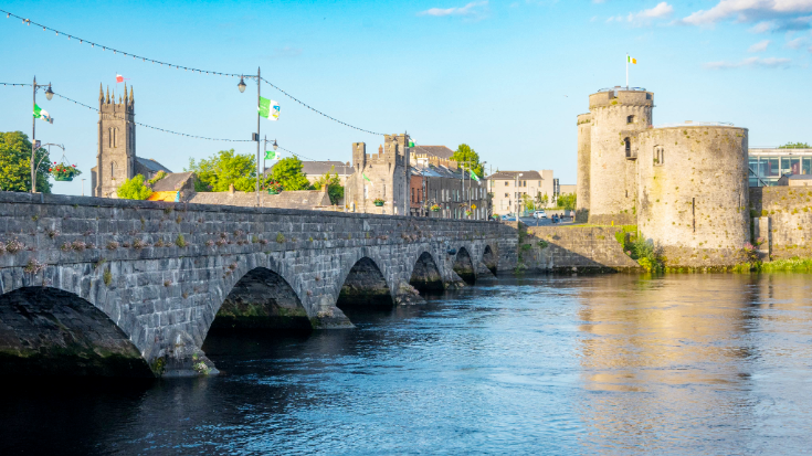 The beige stone King John's Castle with a bridge over the River Shannon in Limerick, Ireland.