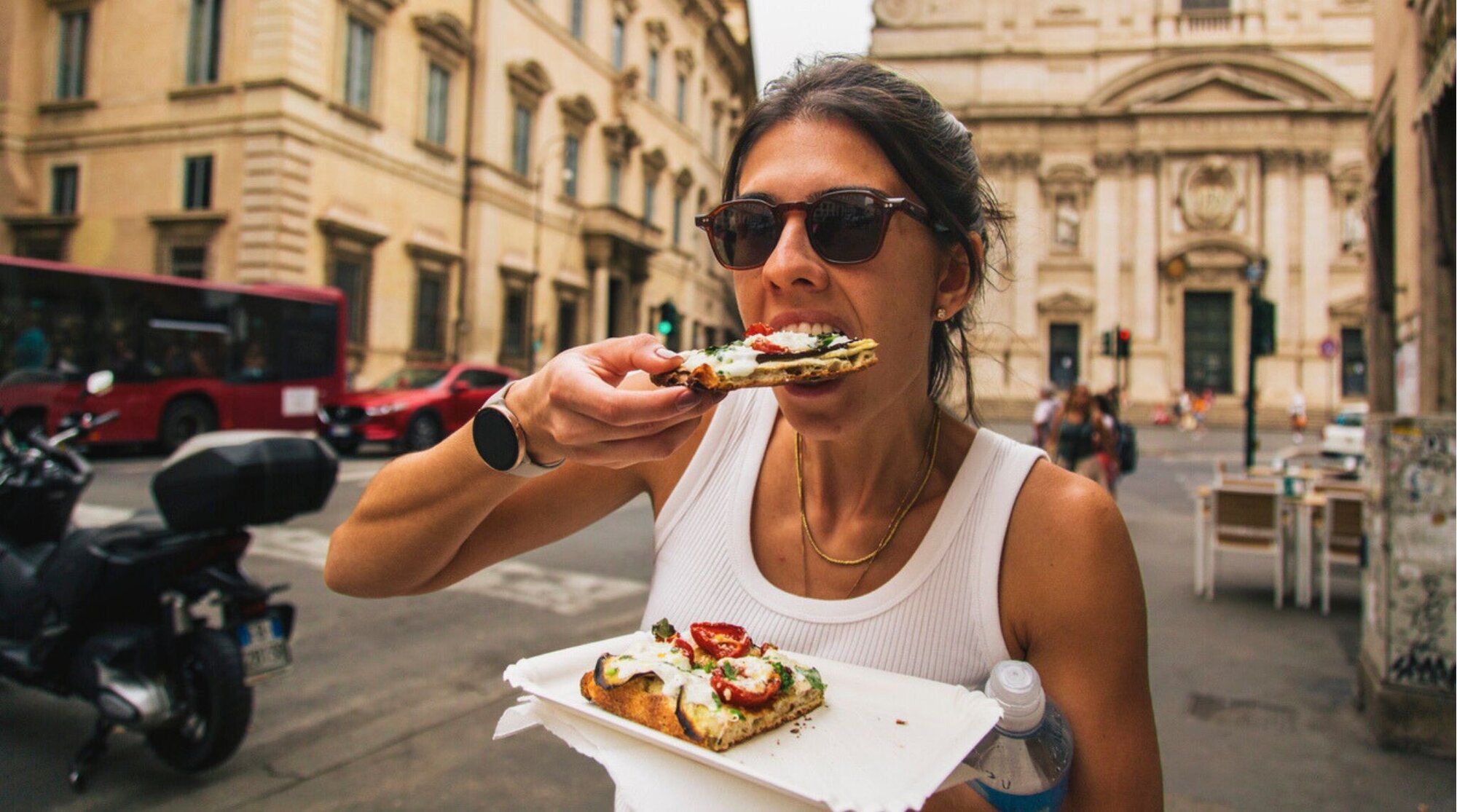 Uma jovem mulher em pé na rua com fatias de pizza. Roma, Itália.