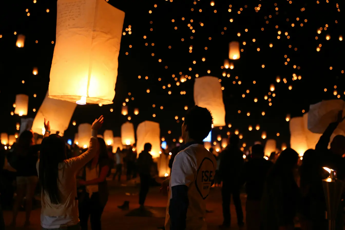 Un grupo de personas lanzando farolillos de papel al aire durante el festival Yi Peng de Tailandia.