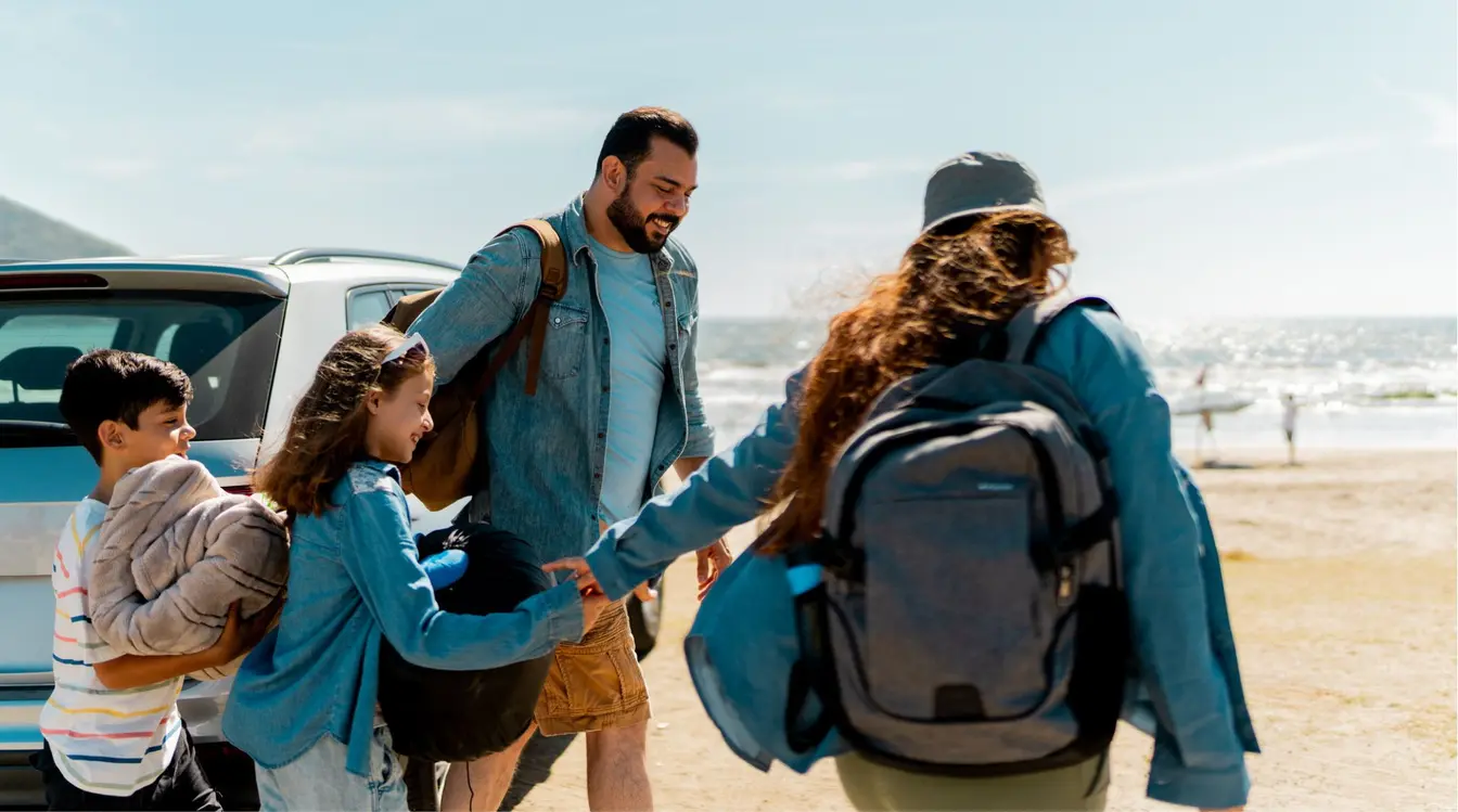 Familia bajando del auto y caminando hacia la playa en un roadtrip por la Península de Yucatán.