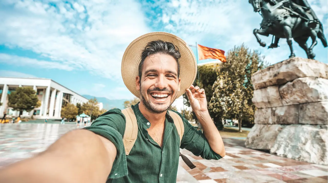 Voyageur prenant un selfie sur la place Skanderbeg à Tirana, en Albanie, pendant son séjour.
