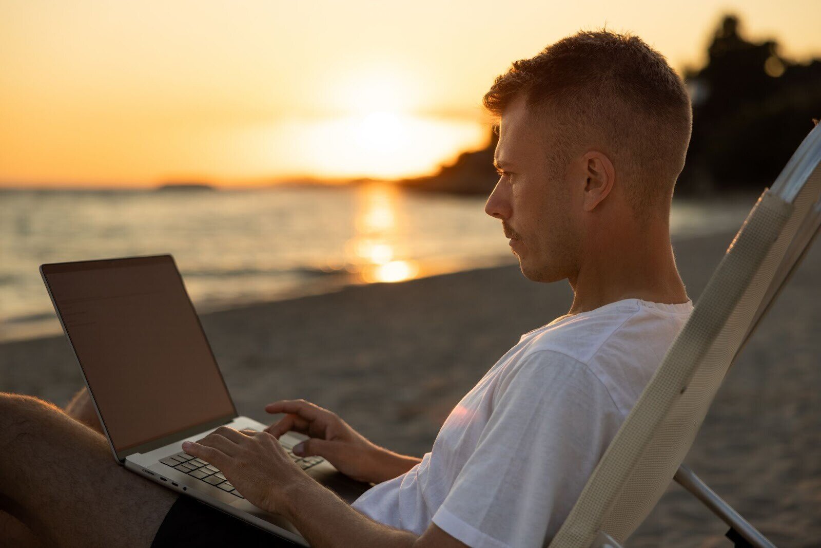 Ein Mann arbeitet mit Laptop am Strand