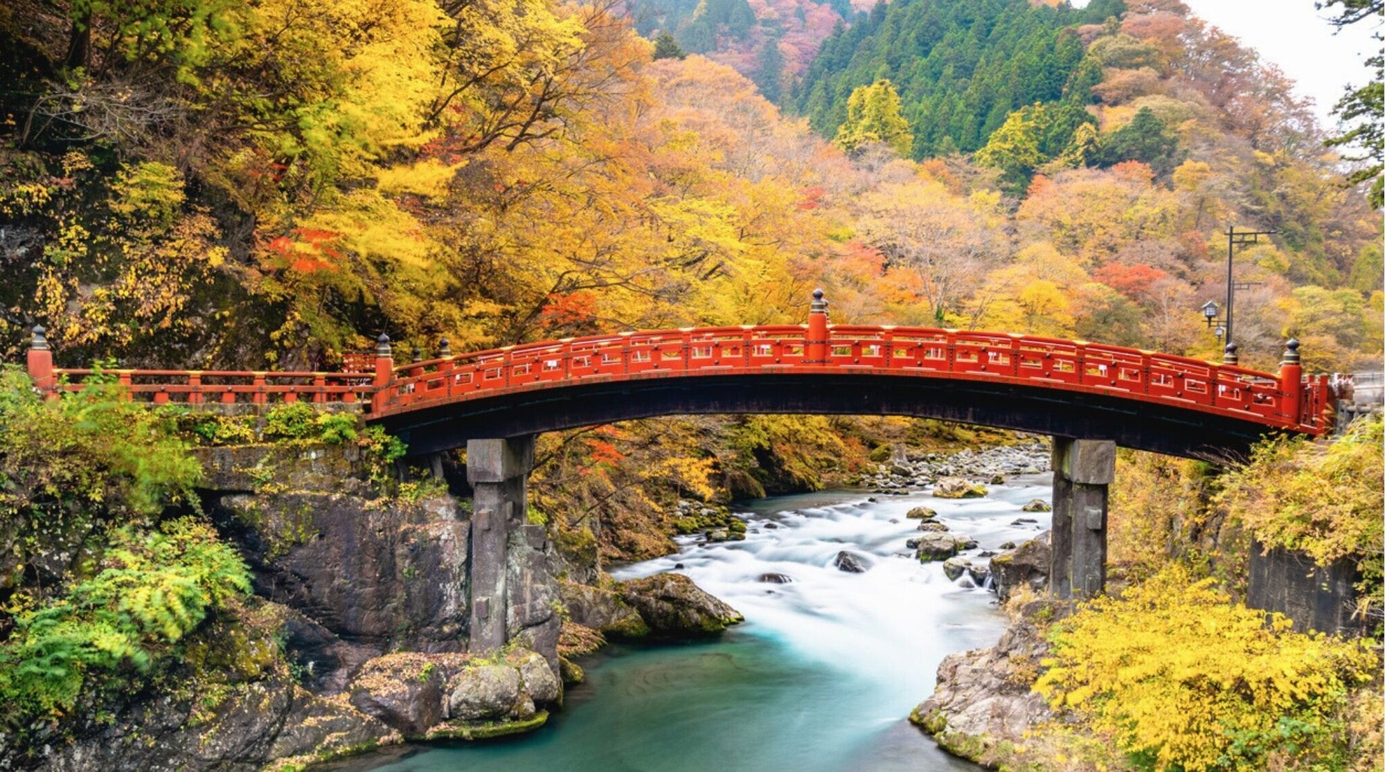 Puente Shinkyo en Nikko rodeado de árboles con hojas amarillas en otoño.