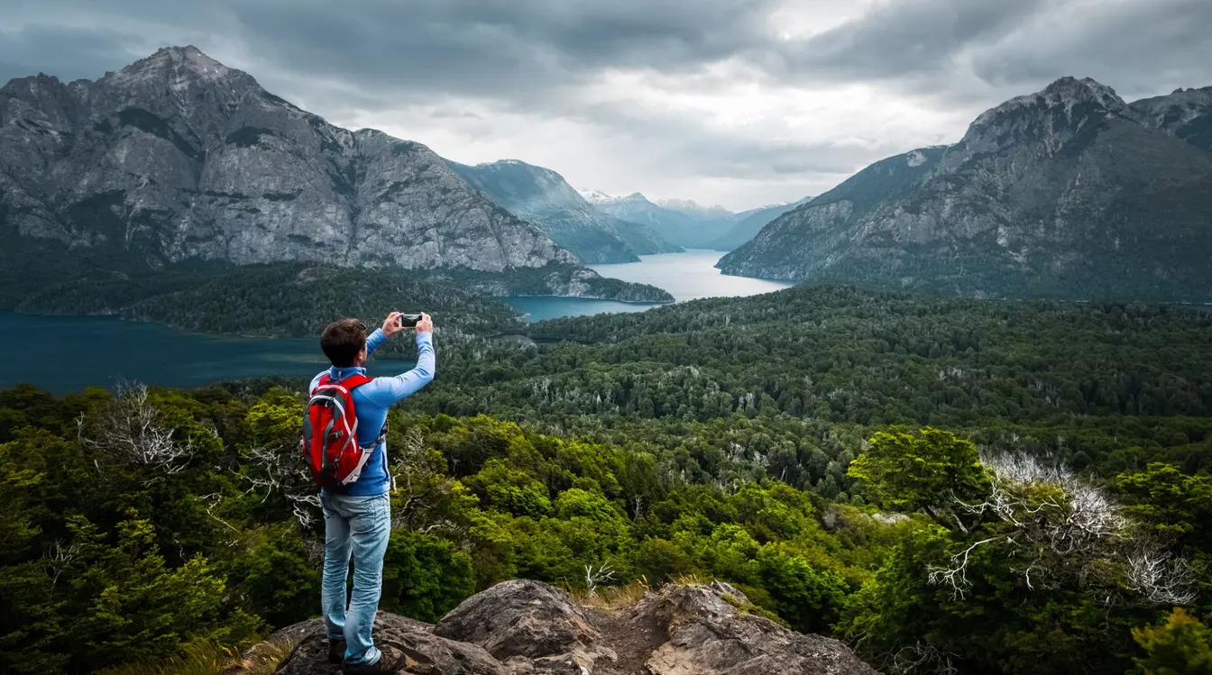 Escursionista in cima a una montagna in Argentina che utilizza lo smartphone con connessione internet durante il viaggio