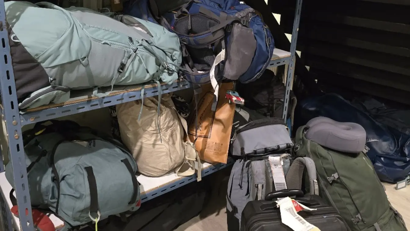 Mochilas y maletas de viajeros apiladas en un estante.