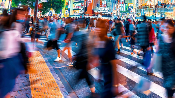 A lively nighttime street scene in Tokyo or Osaka, bustling with people, illustrating the fun that can be had with a reliable eSIM for Japan.