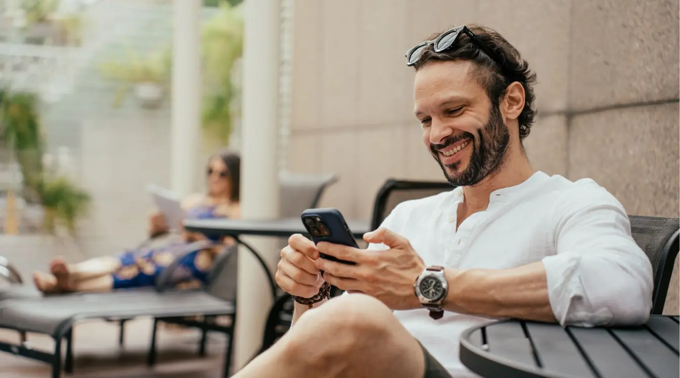 Turista em uma cadeira de descanso mexendo no celular durante as férias.