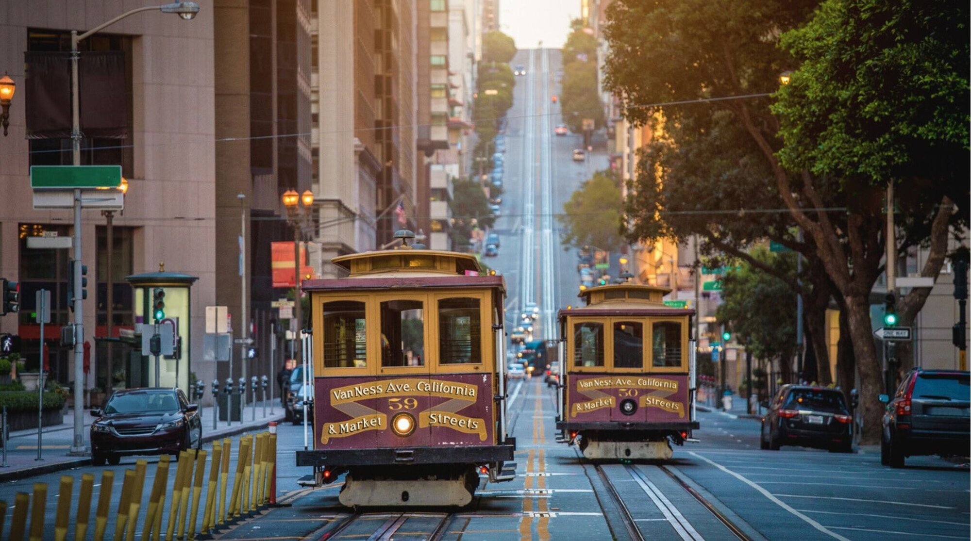 Cable cars subiendo una colina en California Street al amanecer en San Francisco, vista urbana con rascacielos