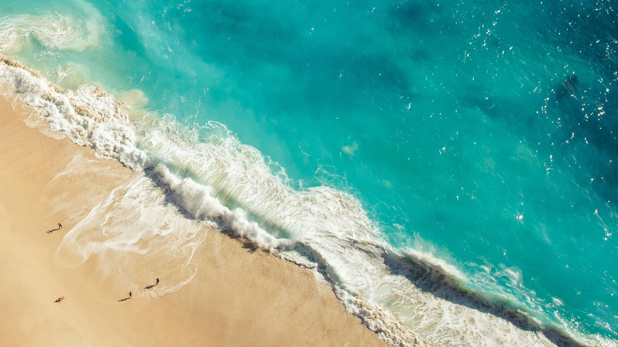 A vibrant blue wave crashes onto the beach in Bali