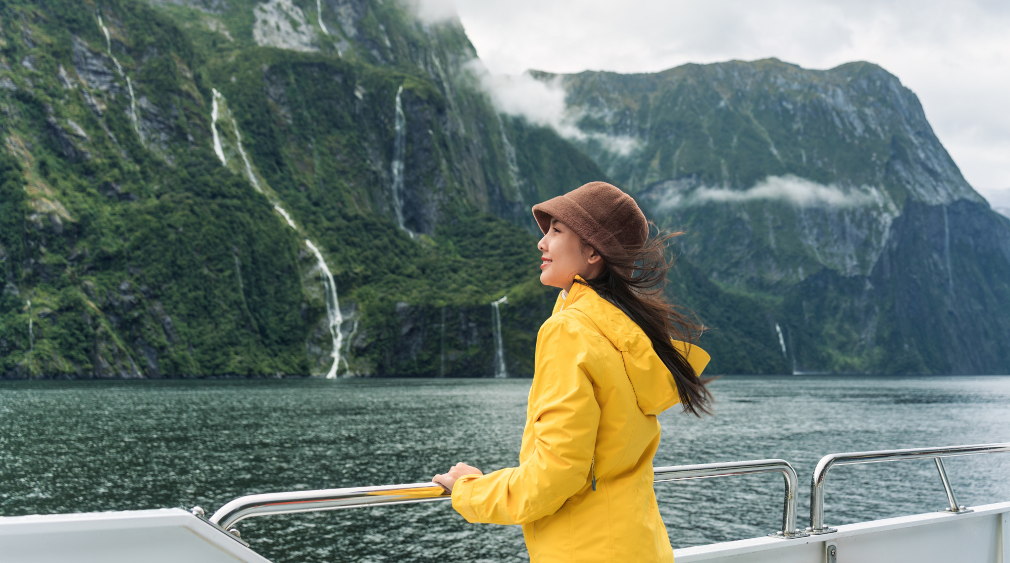 Eine Frau steht auf einem Boot in den Bergen von Neuseeland und benutzt ihre SIM-Karte