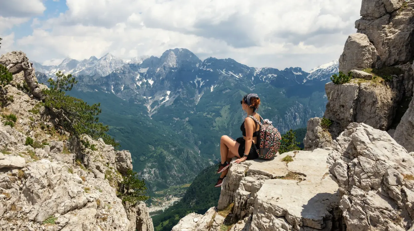 Eine Frau sitzt auf einem Felsen in Albanien und benutzt eine eSIM