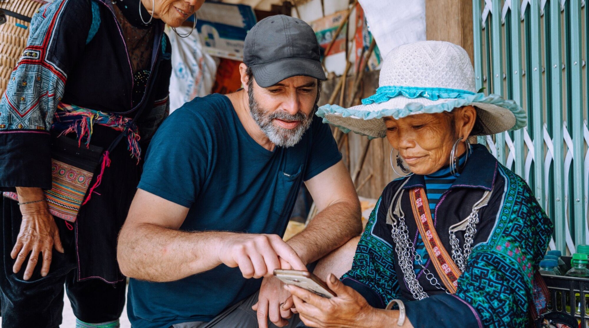 voyageur utilisant l'application itranslate avec deux femmes locales