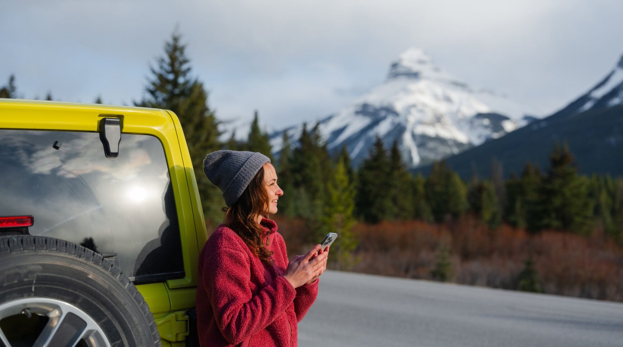 Tourist using her phone while roadtripping through the Canadian mountainscape.