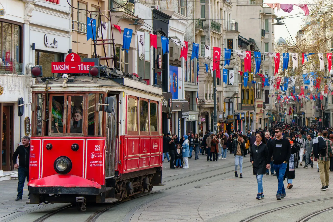 Imagen de un tranvía de color rojo y blanco circulando por la concurrida avenida peatonal Istiklal para ilustrar qué hacer en Estambul.