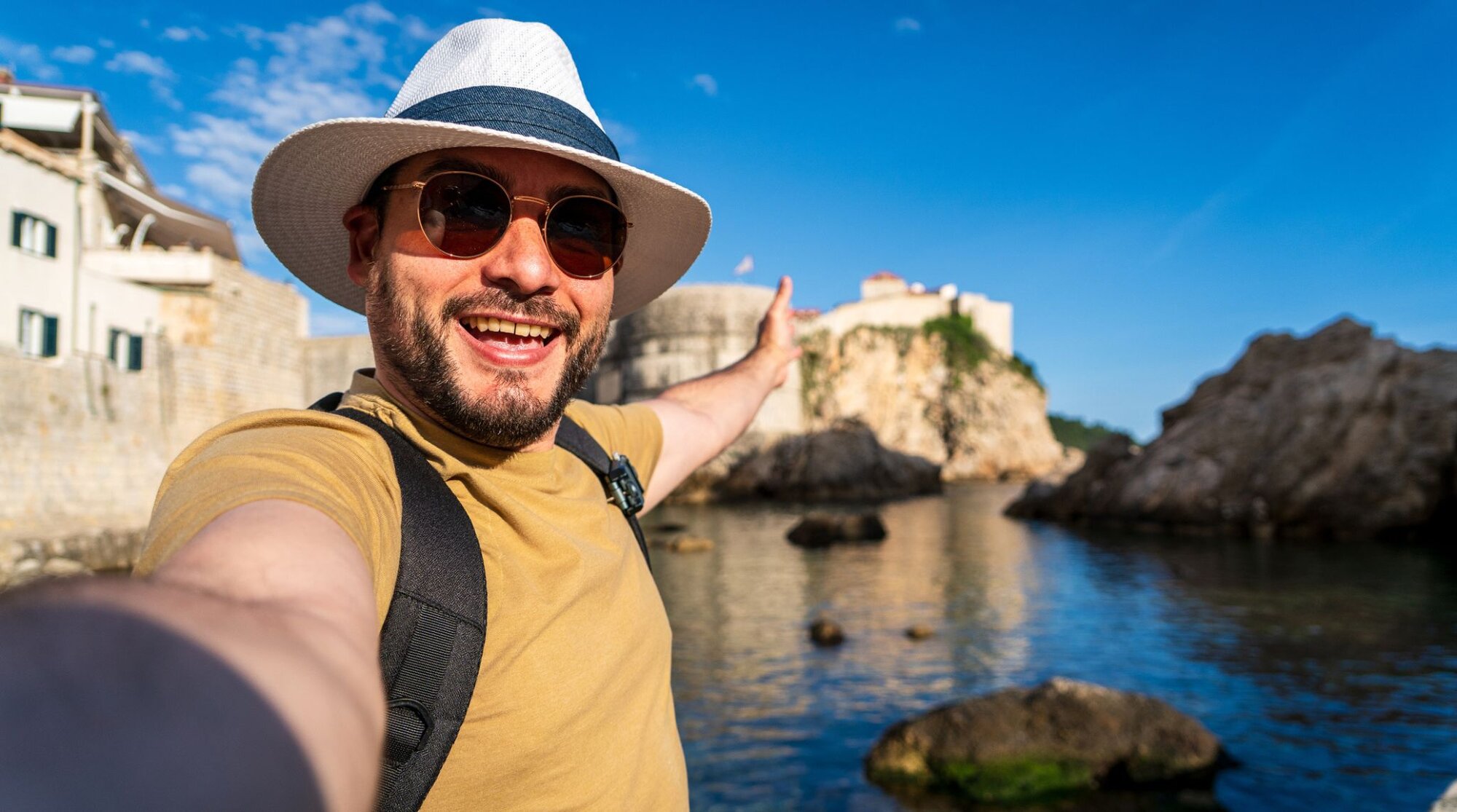 Turista che si scatta un selfie con lo smartphone davanti a una città storica europea durante un viaggio all’estero