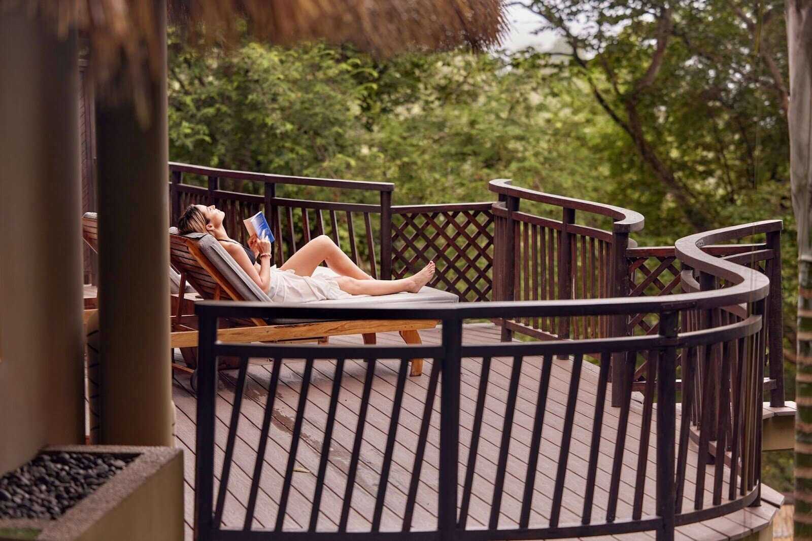 Eine Frau liegt während der Regenzeit auf einer Veranda auf den Seychellen und liest ein Buch im Warmen.