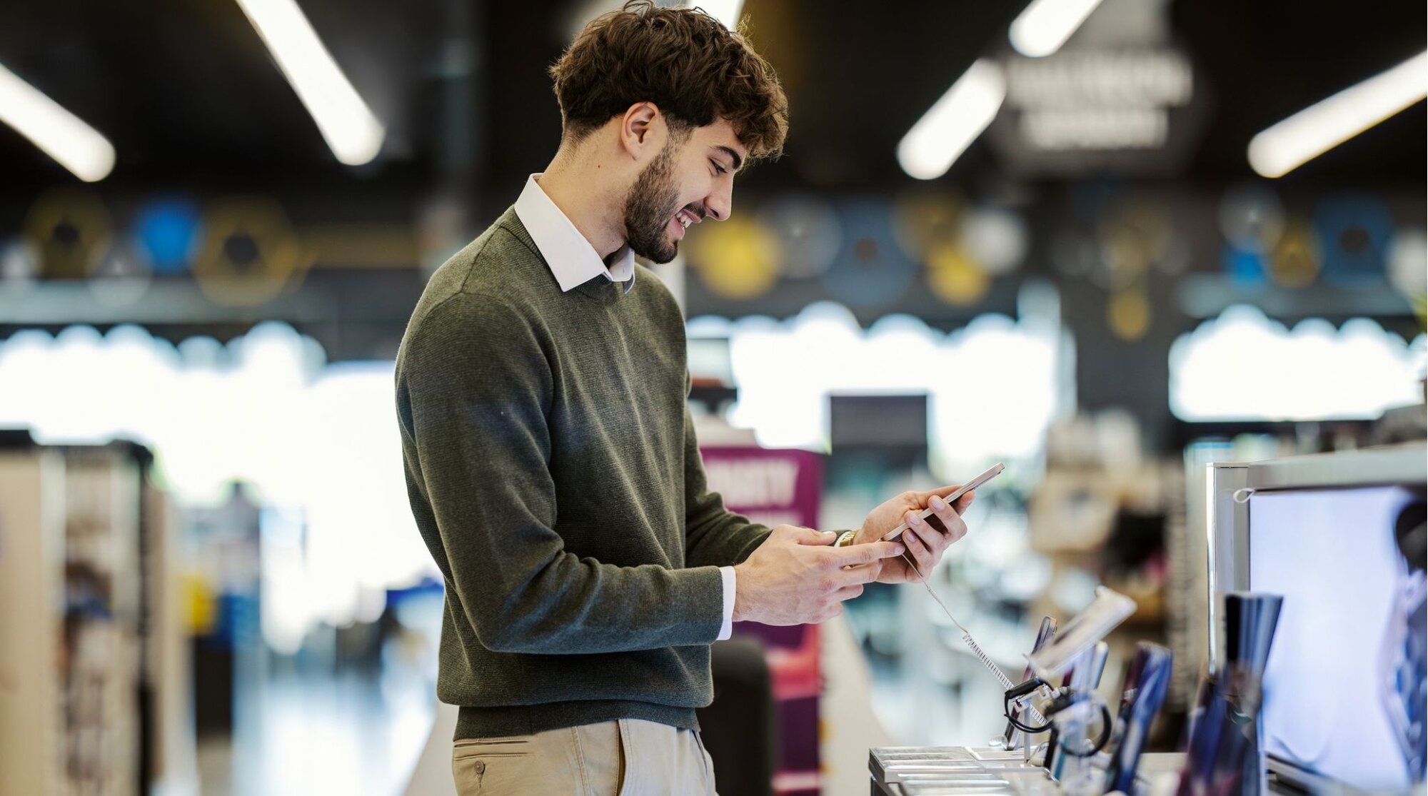 Jovem adulto comprando um smartphone novo em loja de eletrônicos.