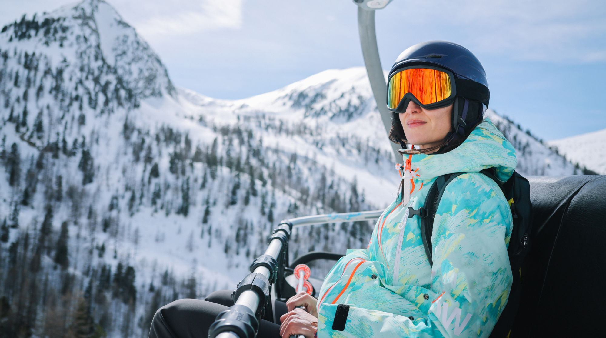 Donna su uno skilift nelle Alpi francesi con vista sulle montagne innevate, esempio di esperienza sciistica in Europa.