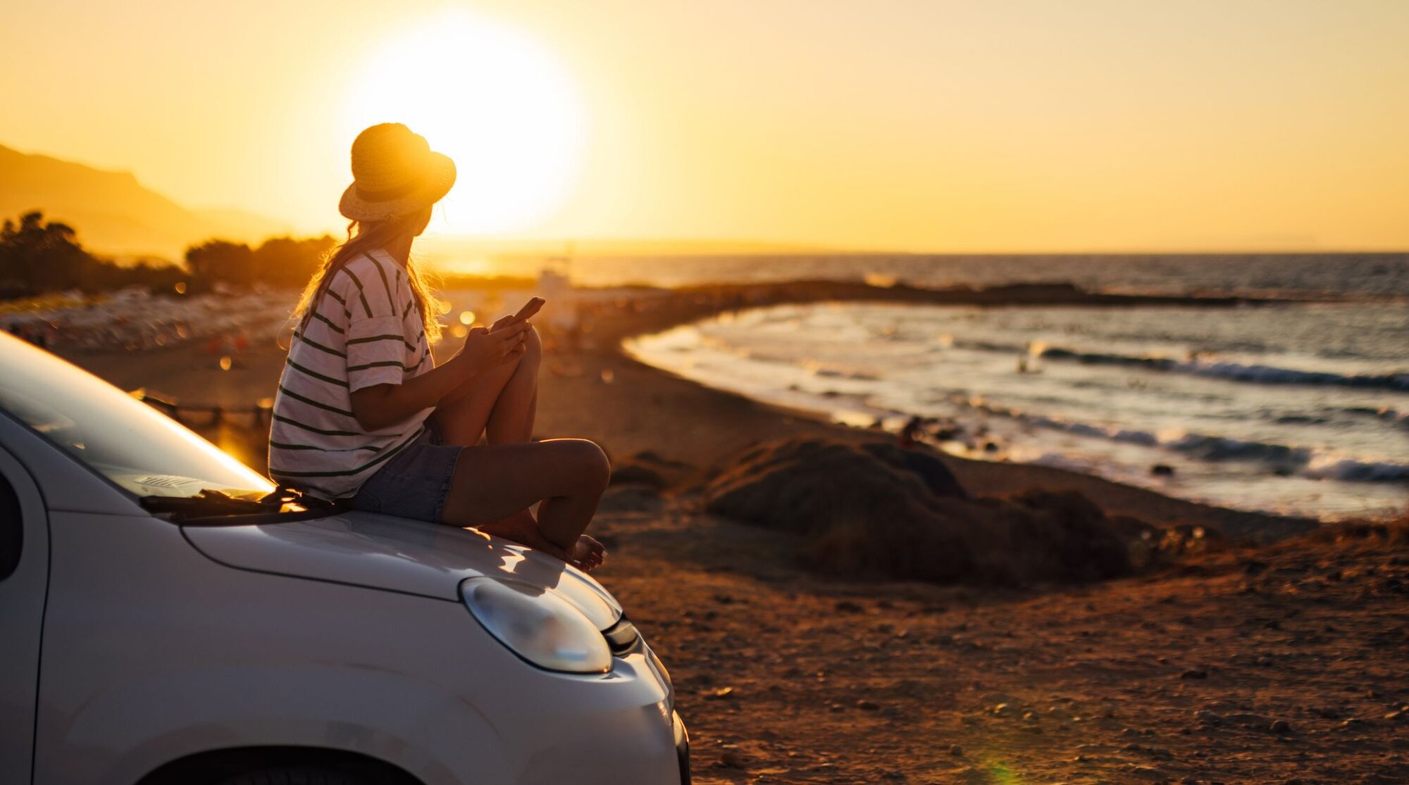 A young woman is using her Unlimited eSIM to take and share pictures of the sunset.