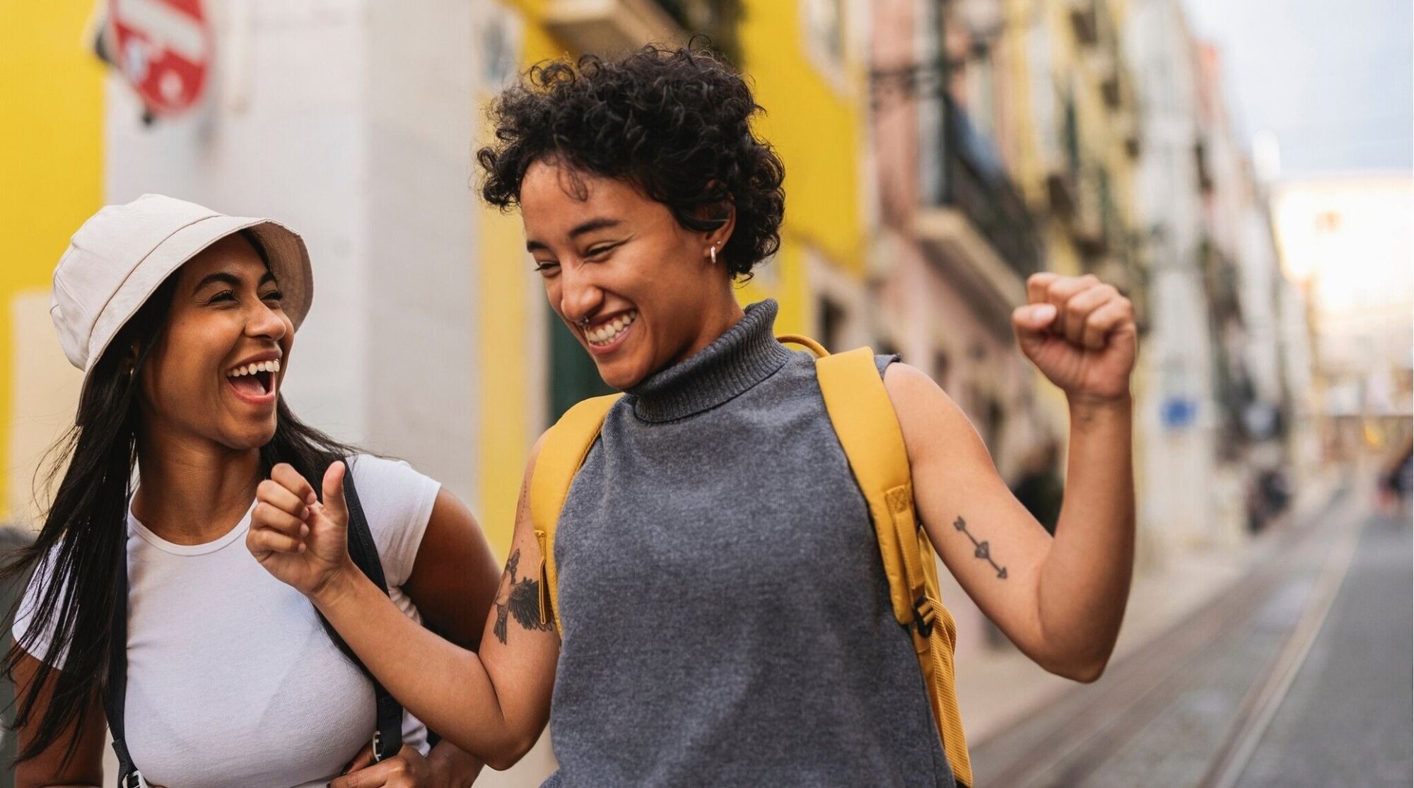 Dos turistas caminando y riendo por una calle de Lisboa, viaje en primavera.