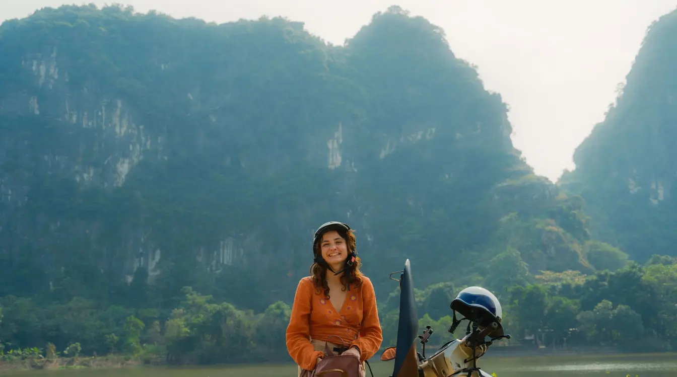 Eine Frau steht vor einem Berg in Vietnam und steigt auf einen Roller