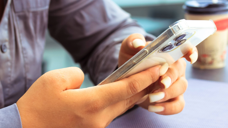 A close up image of a woman with a grey shirt on installing an eSIM on her iPhone 12 Pro, to illustrate a blog post entitled 'Is My iPhone eSIM-Compatible?'