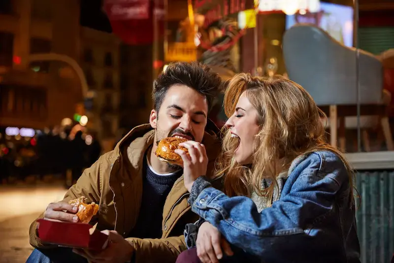 Pareja comiendo comida callejera de noche en Madrid, España.