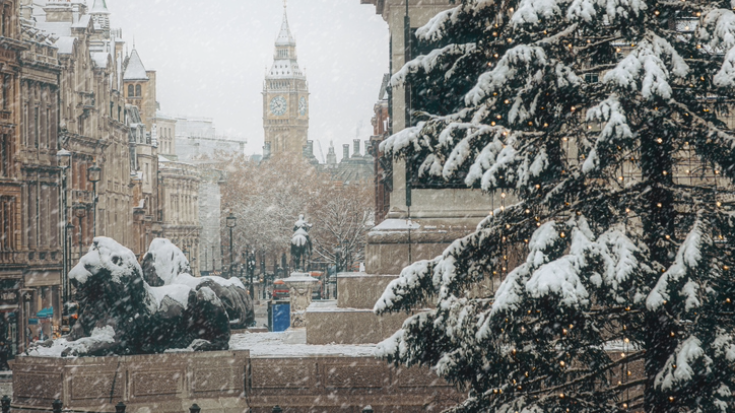 A photograph of heavy snow in the foreground and in the background is the clock Big Ben and Westminster covered in winter snow, to illustrate a blog post entitled 'Things to do in London in December'. 
