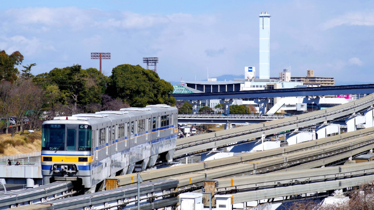An image of an overland train on the JR Keiyo Line in Chiba with the Summer Sonic Festival venue behind the train. 