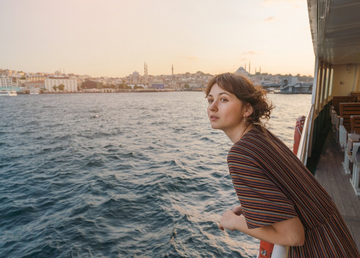 Mujer viajando en un ferry por el Bósforo, en Estambul, al atardecer.