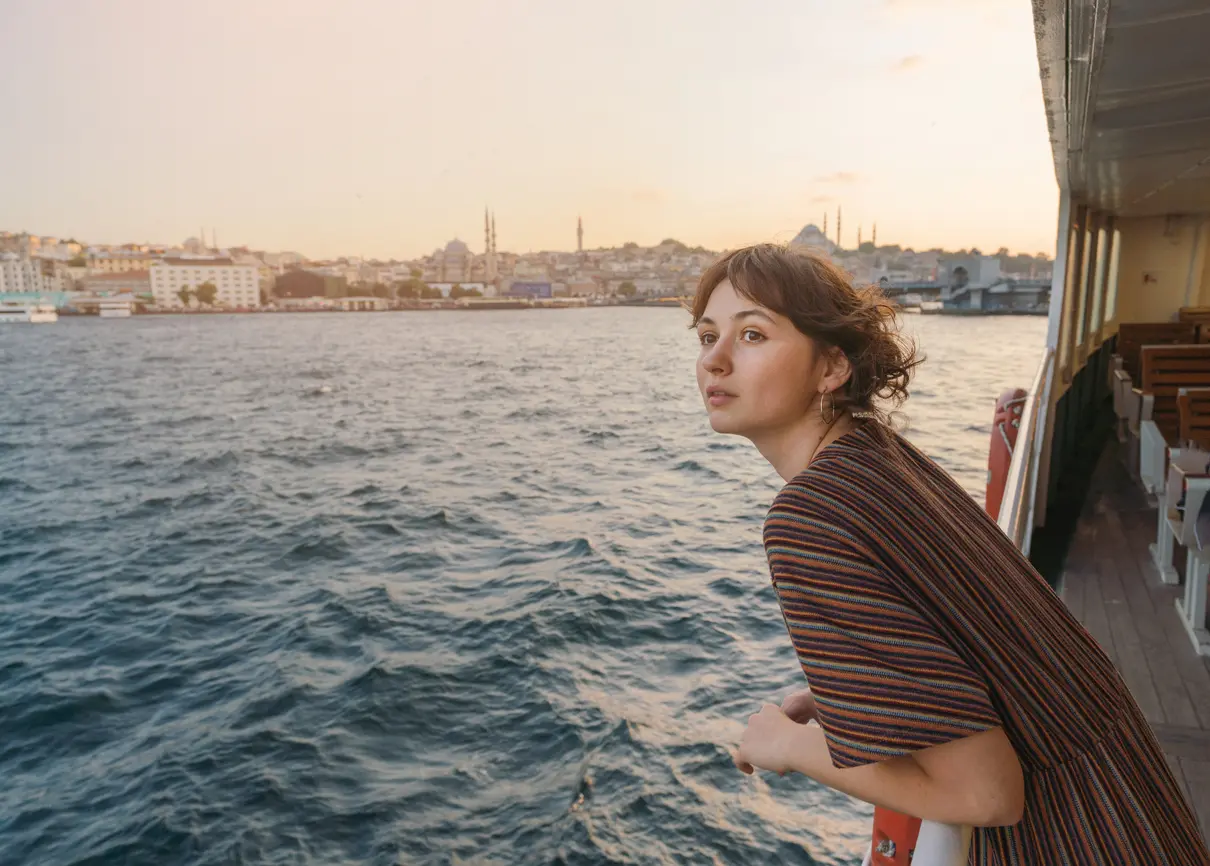 Mujer viajando en un ferry por el Bósforo, en Estambul, al atardecer.