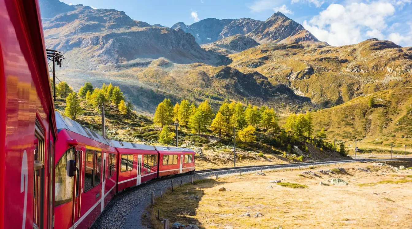 View of the red Bernina Express train passing through the Swiss Alps.