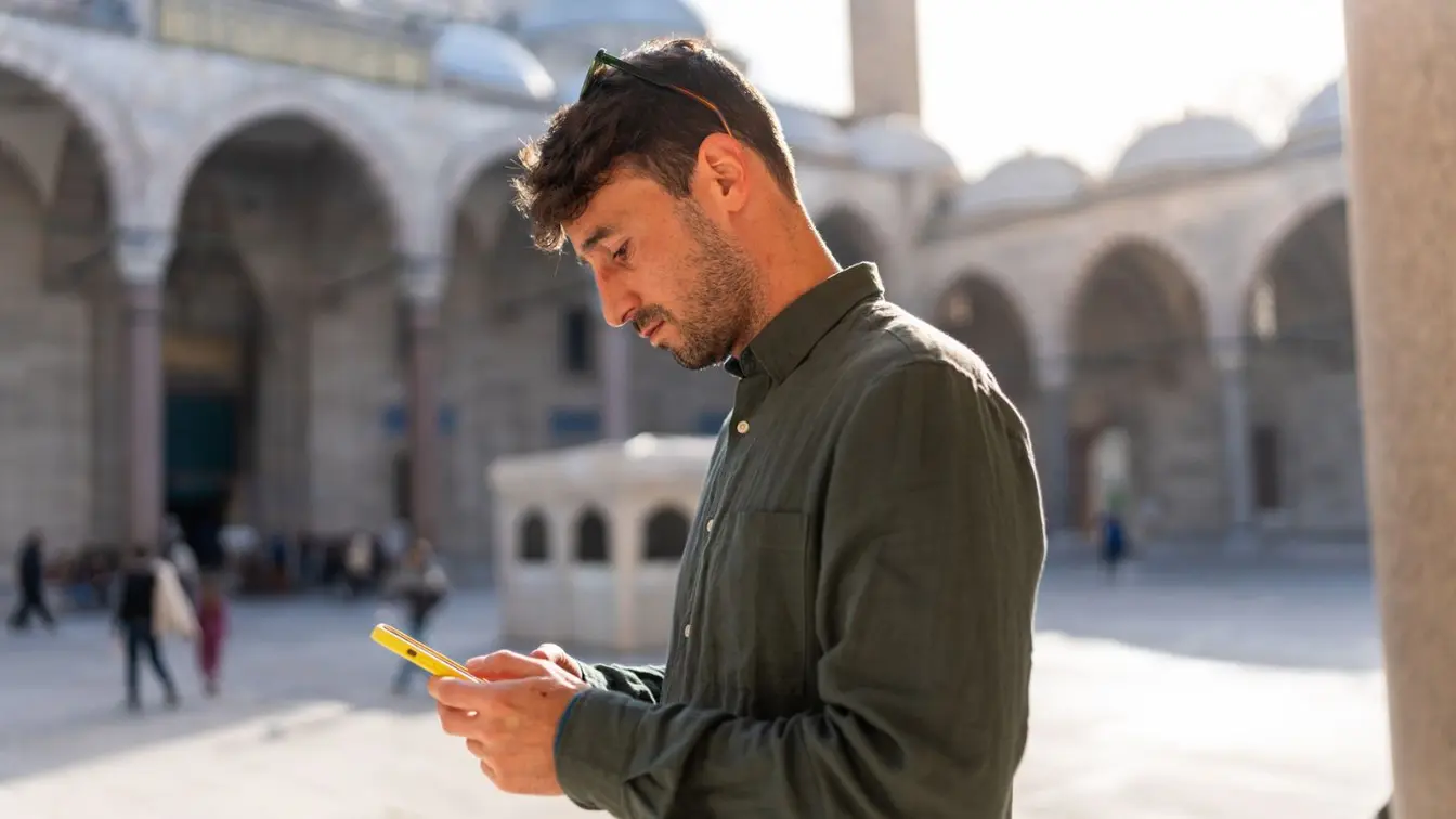 Ein Mann steht vor einem Tempel in Istanbul und benutzt mobile Daten in der Türkei auf seinem Handy.