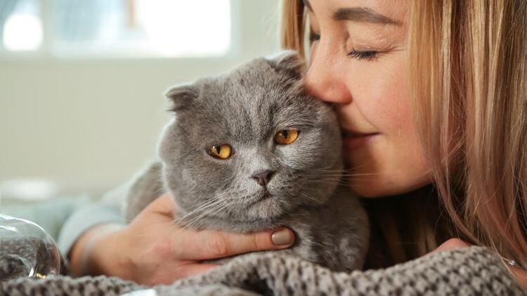 woman kissing cats cheeks