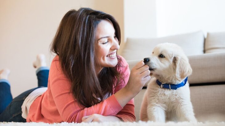 woman giving a puppy a treat