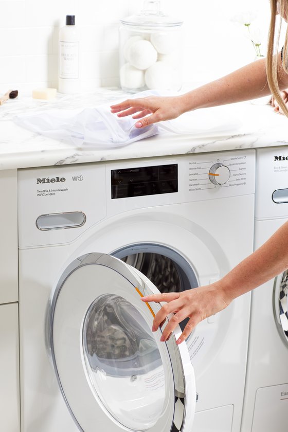 Woman adding garments to washing machine
