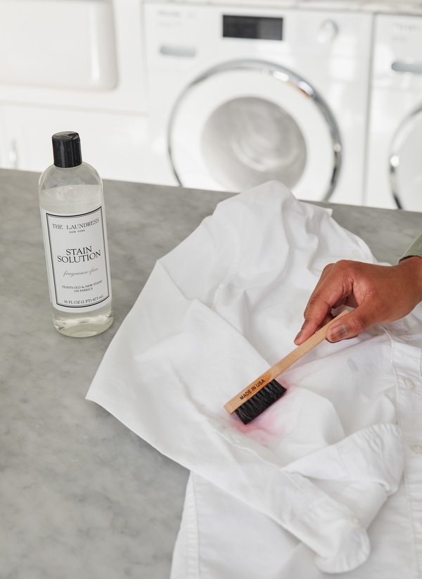 Person using The Laundress Stain Brush to spot treat stain