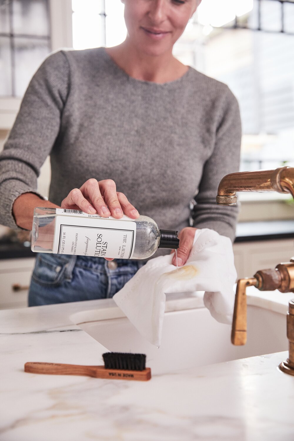 woman holding the laundress stain solution and pouring it onto a stained cloth over a sink