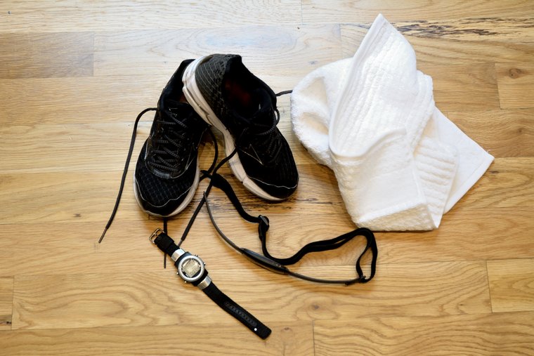 Black sneakers on floor with white towel and watch