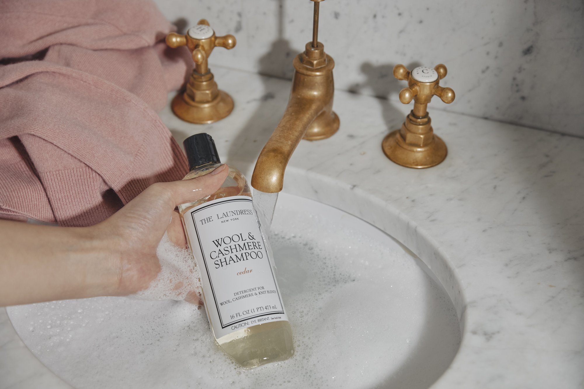 Wool and Cashmere Shampoo in a marble sink with bronze faucet.