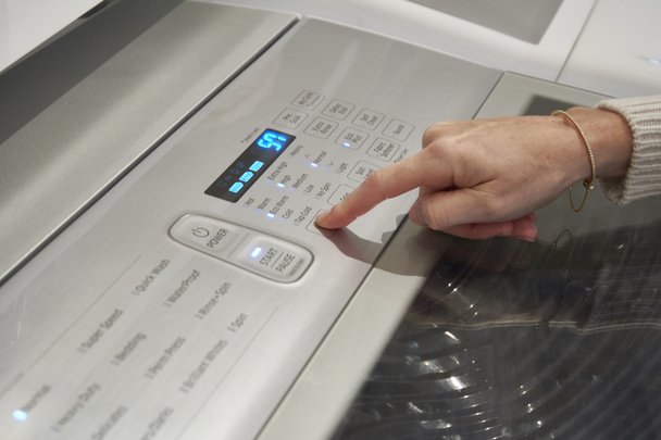 Person changing settings on washing machine