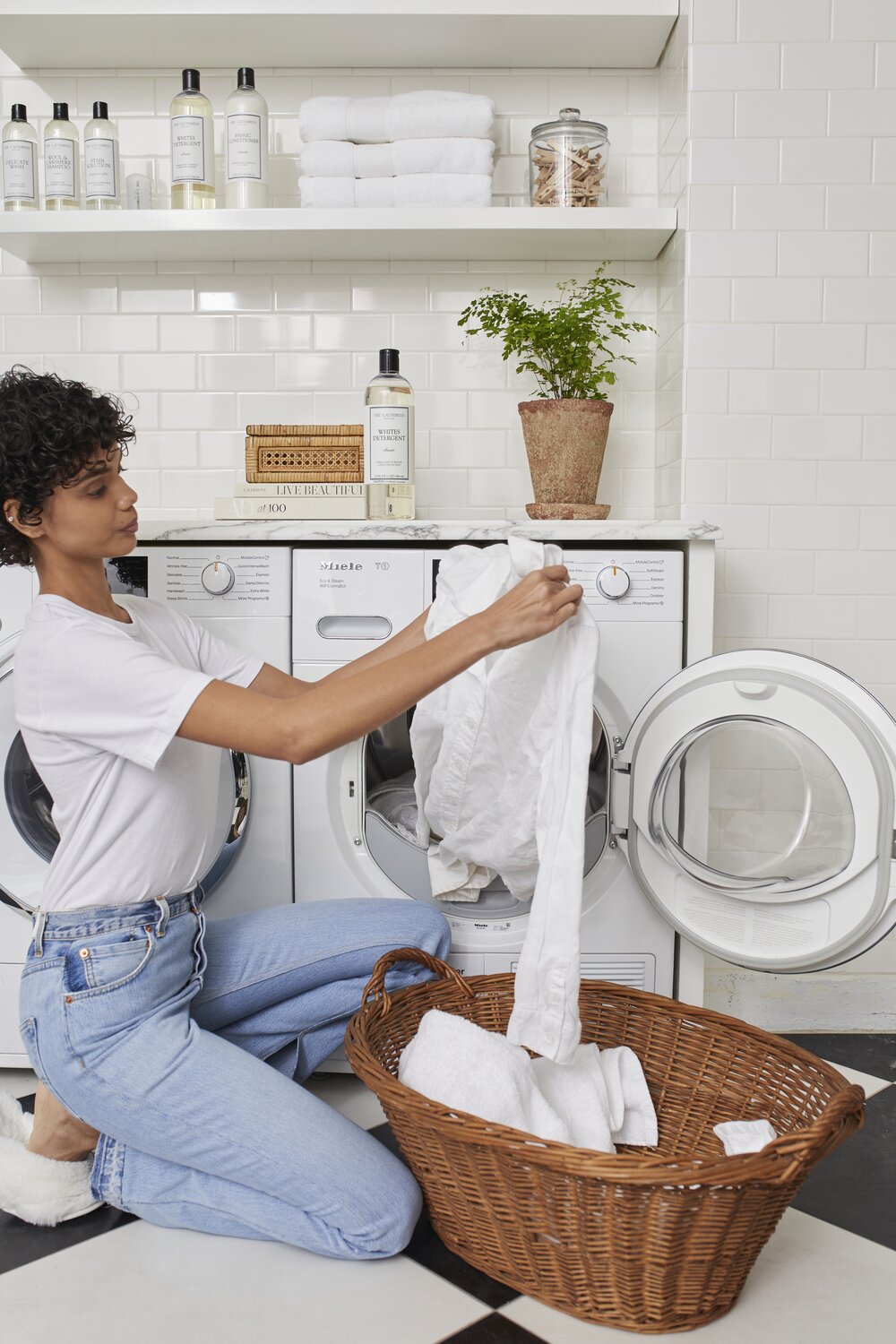 Girl taking white laundry out of a dryer with the laundress Whites Detergent next to the machine