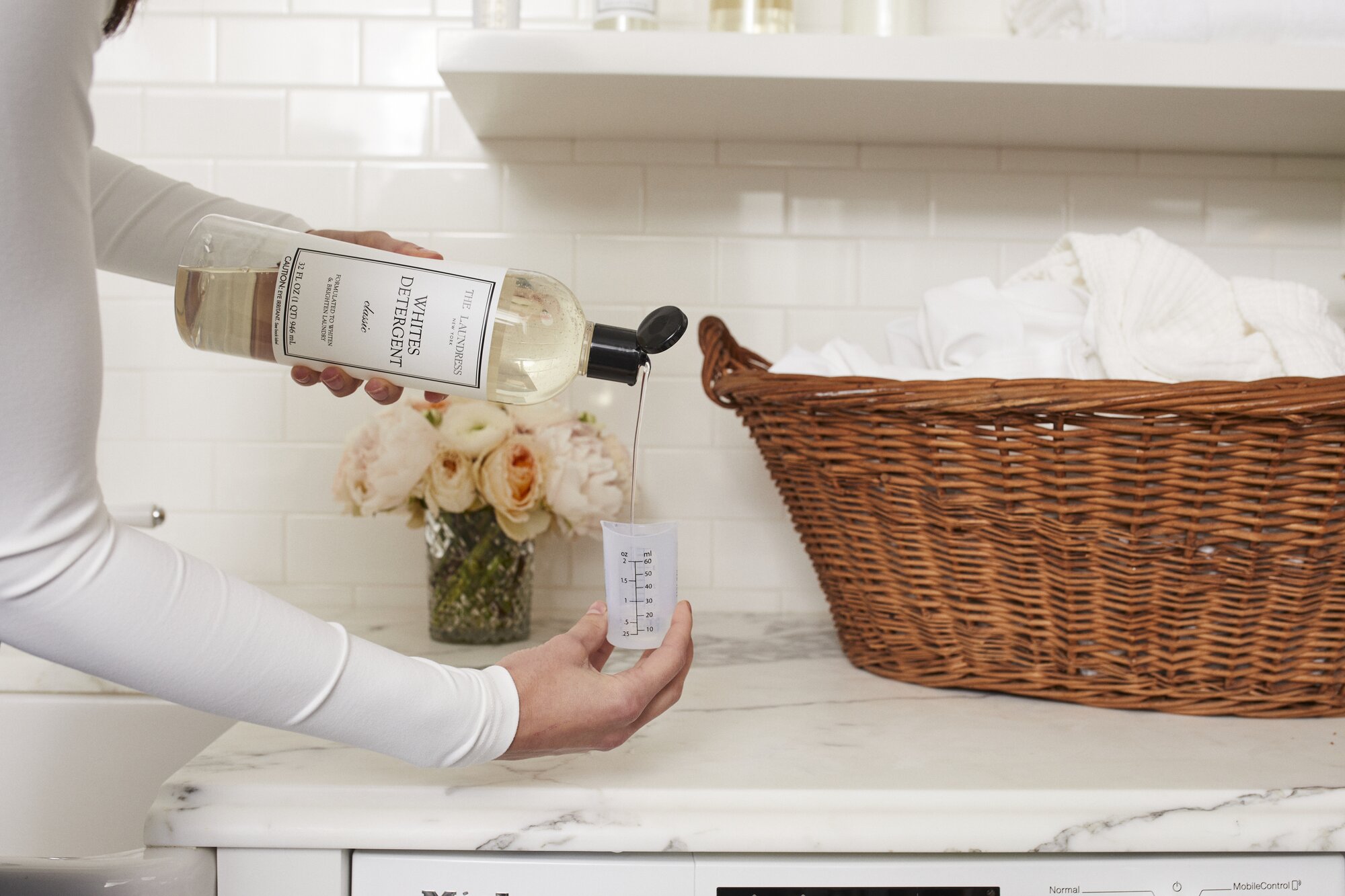 pouring the laundress whites detergent into silicone measuring cup before dosing into washing machine