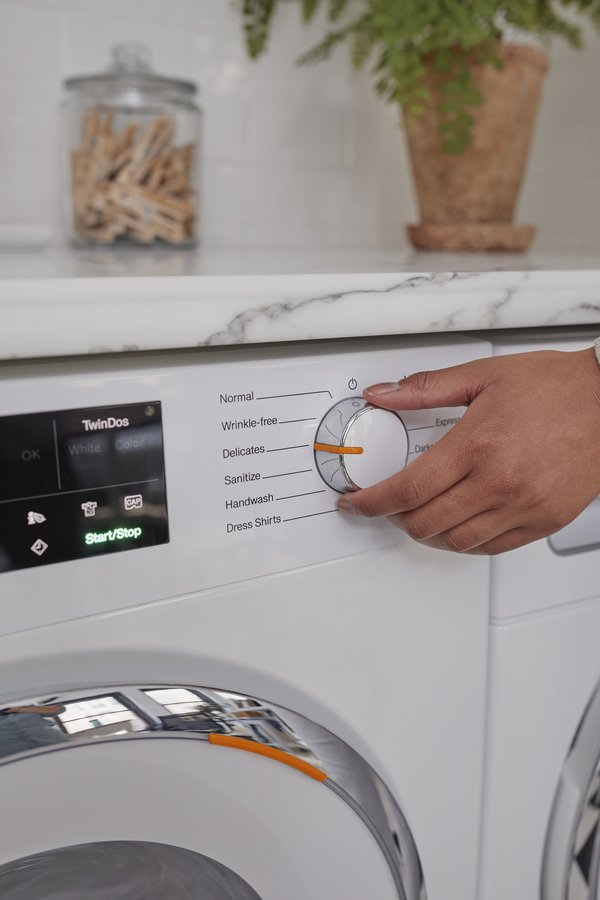 A washing machine being adjusted to the delicates setting.