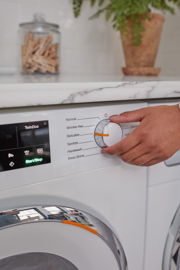 A hand adjusts a washing machine to the 