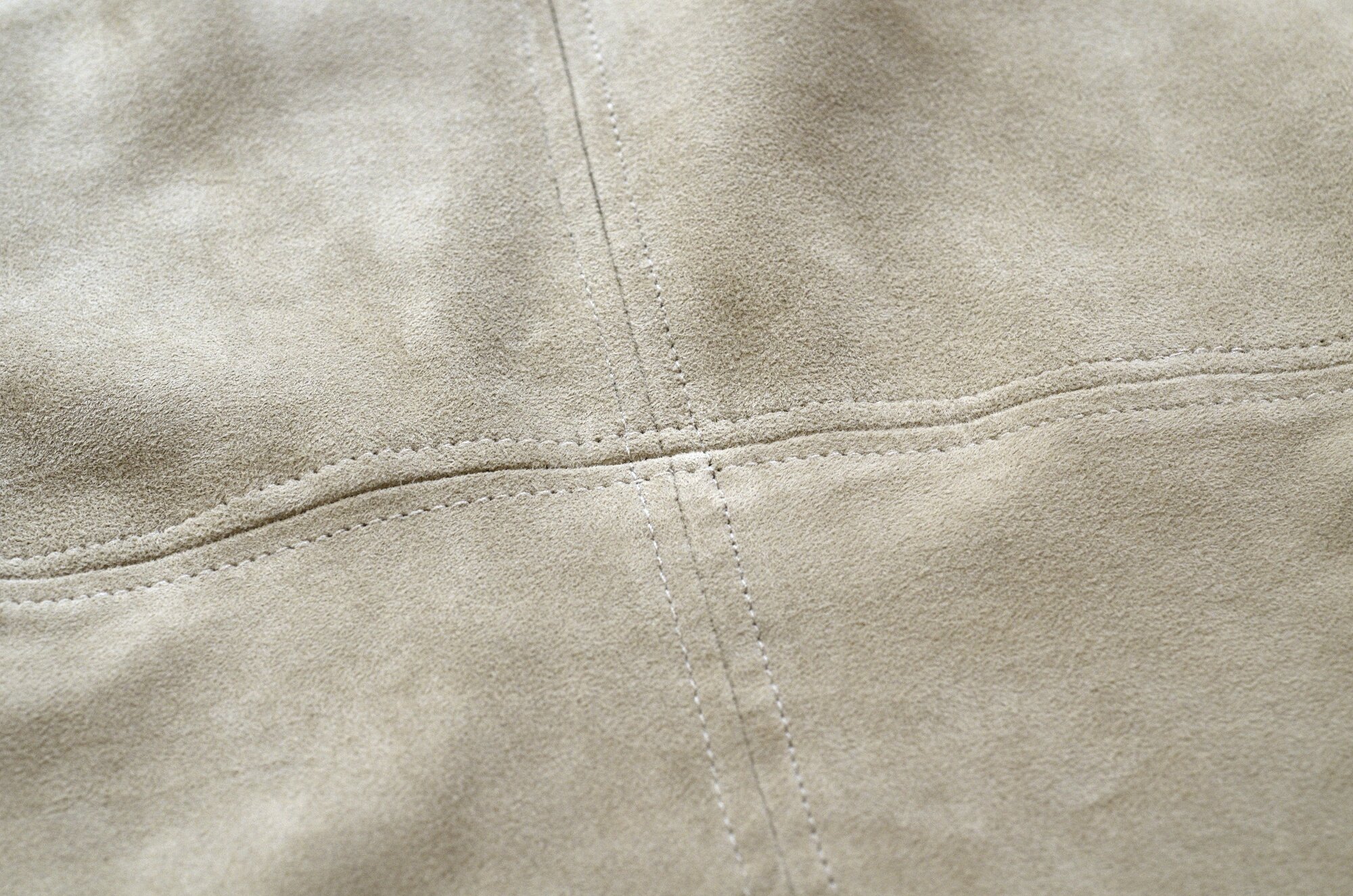 Beige suede fabric stitched with intersecting horizontal and vertical seams, creating a grid pattern, which is about to be cleaned with The Laundress' dry cleaning method.