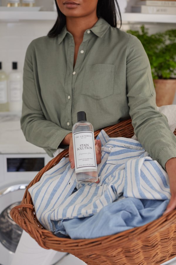 Woman holding The Laundress Stain Solution in laundry room