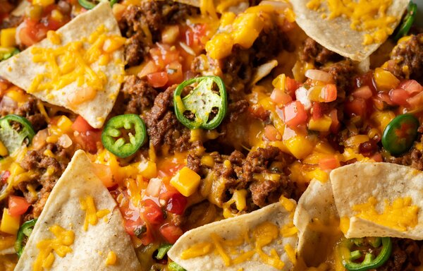 nachos with black beans and jalapenos on a baking sheet.