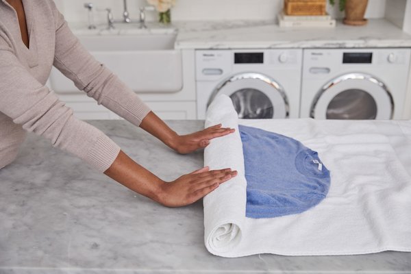 rolling up cashmere sweater in a white towel to dry